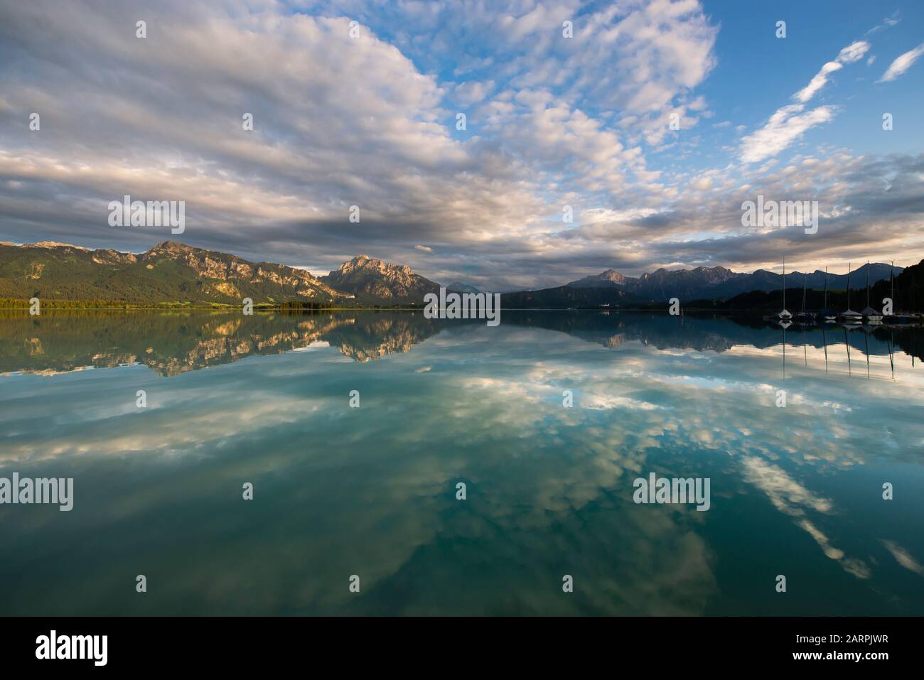 Schloss Neuschwanstein, Schloss Hohenschwangau und die bayerischen Alpen bei Sonnenuntergang spiegeln sich im Forggensee in Bayern wider Stockfoto