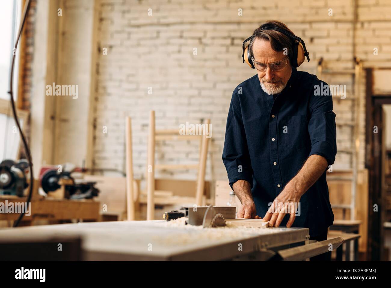 Leitender Tischler für Kopfhörer mit Geräuschminimierung, die an der Sämaschine arbeiten Stockfoto