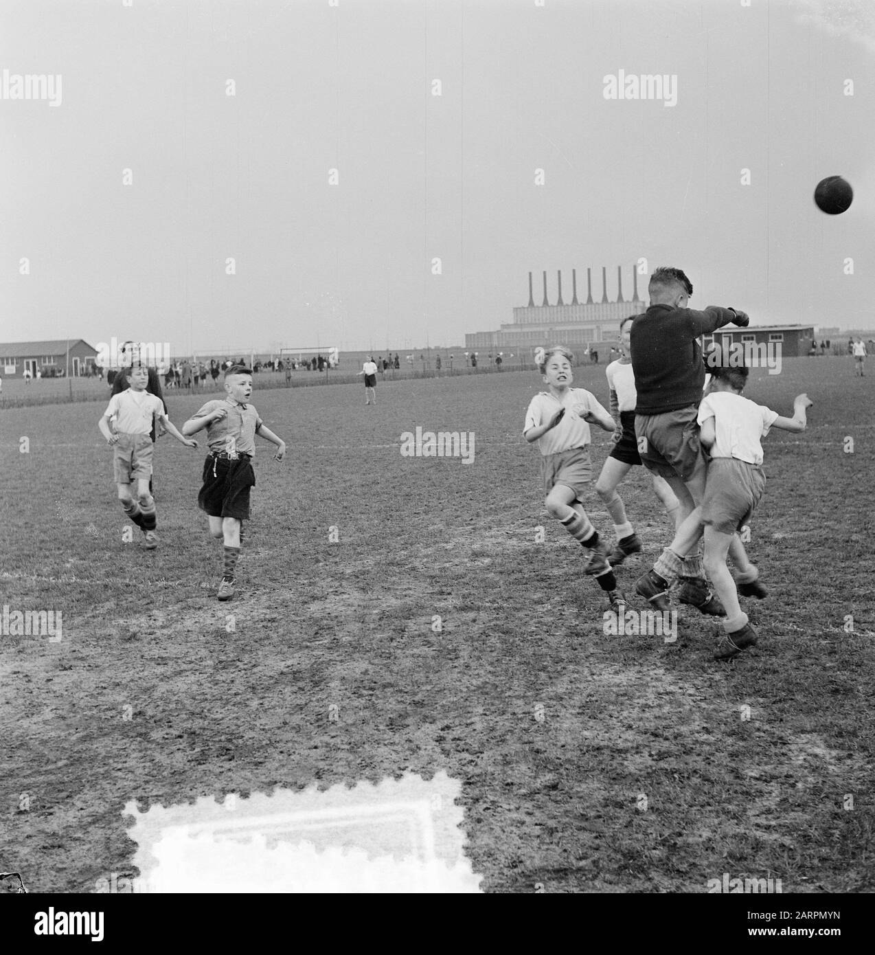 Schulfußball-Anmerkung: Aufgabe Trouw. Torhüter schlägt Ball weg. Im Hintergrund Kraftwerk Hemweg, das 1952 in Betrieb genommen wurde. Standort Sloterdijk? Datum: 15.April 1953 Ort: Amsterdam Schlagwörter: Schulfußball, Name der Sporteinrichtung: Trouw Stockfoto
