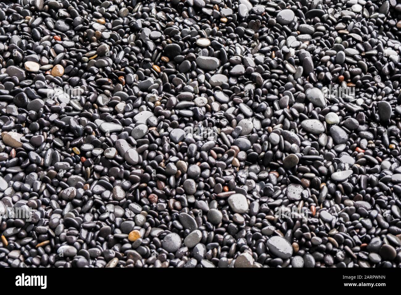 Hintergrund schwarzer Kiesel und Steine an den schwarzen Sandstränden von Reynisfjara in Island Stockfoto