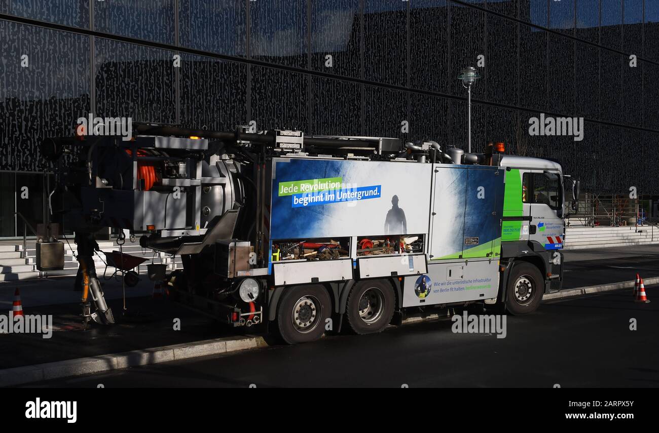 Berlin, Deutschland. Januar 2020. Vor dem Axel Springer-Gebäude in Berlin-Mitte steht ein Spezialfahrzeug der Berliner Wasserbetriebe zur Kanalisationsarbeit; ein Arbeiter läuft mit einem Schubkarren gegen das Licht vorbei. Kredit: Sonja Wurtscheid / dpa / Alamy Live News Stockfoto