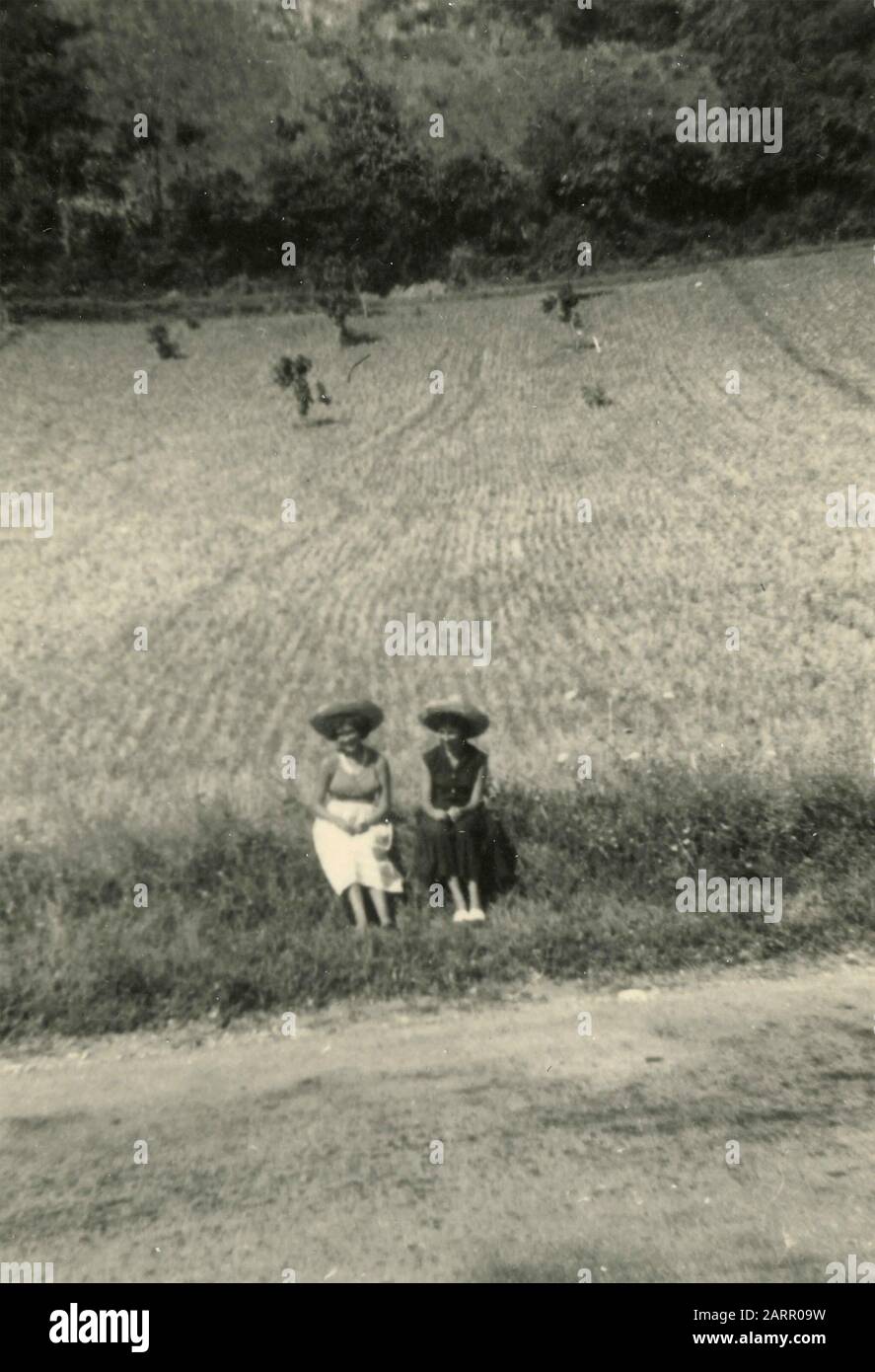 Zwei Frauen mit Krähhut an der Grenze einer Landstraße, Italien 1950er Jahre Stockfoto