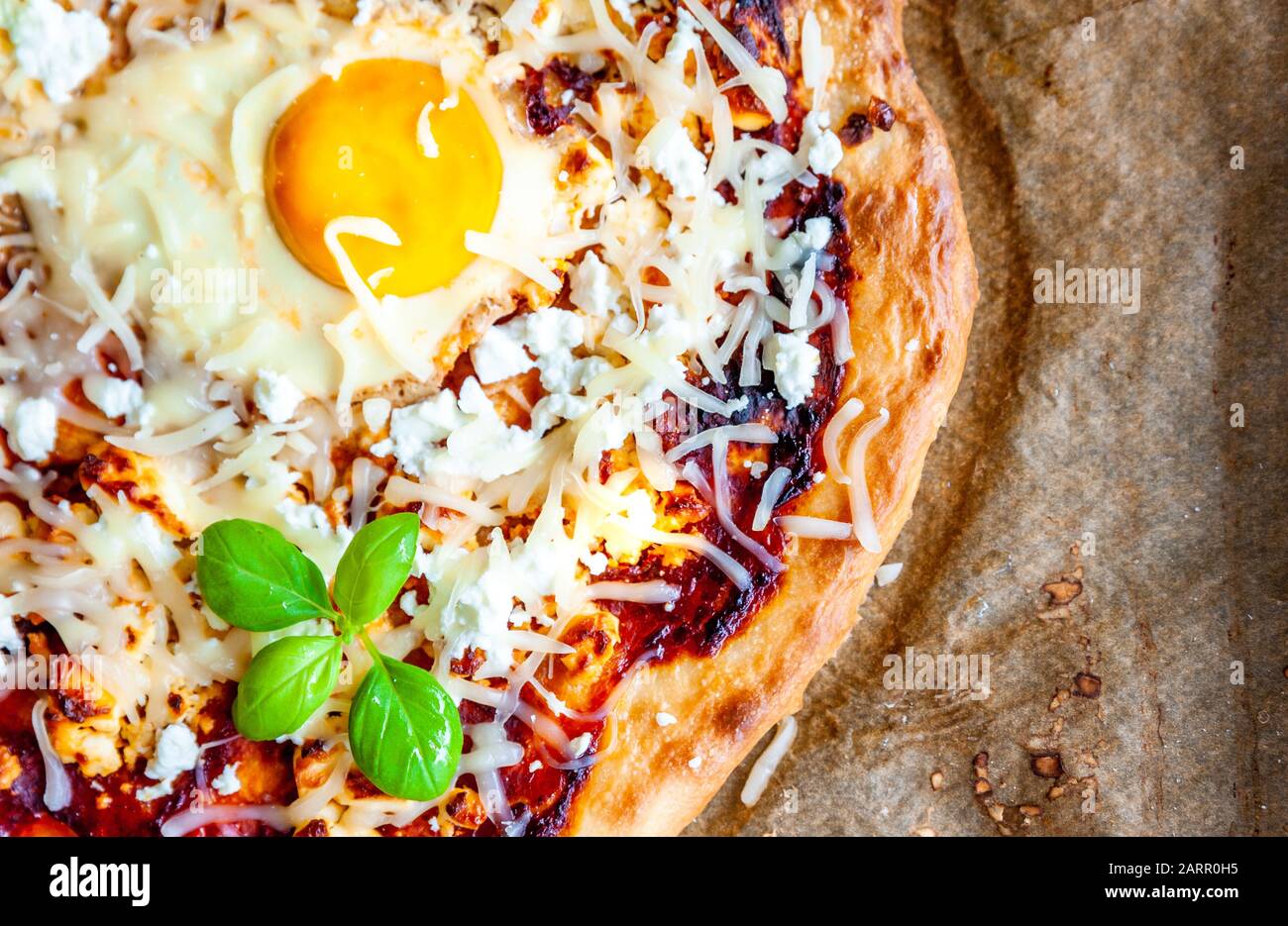 Detailaufnahme einer Pizza mit Ei, Käse und Kräutern. Rustikale Szene und dramatisches Licht. Stockfoto