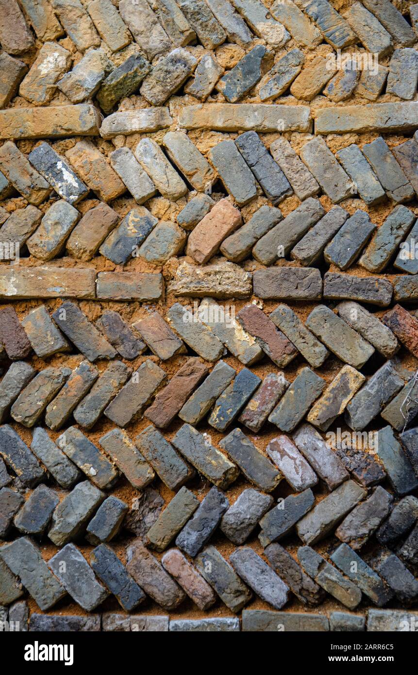 Zick-Zack-Reihen aus strukturierten, handgefertigten Backsteinen, die Teil einer Mauer im alten chinesischen Dorf sind Stockfoto