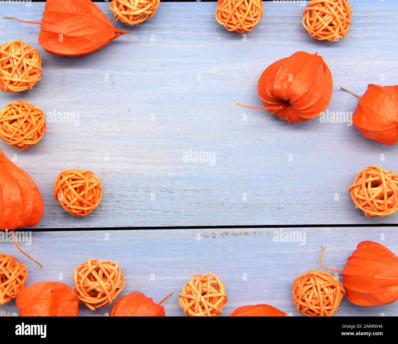 Leuchtend orangefarbene Physalis und Korbbkugeln auf blauem Holzhintergrund. Stockfoto
