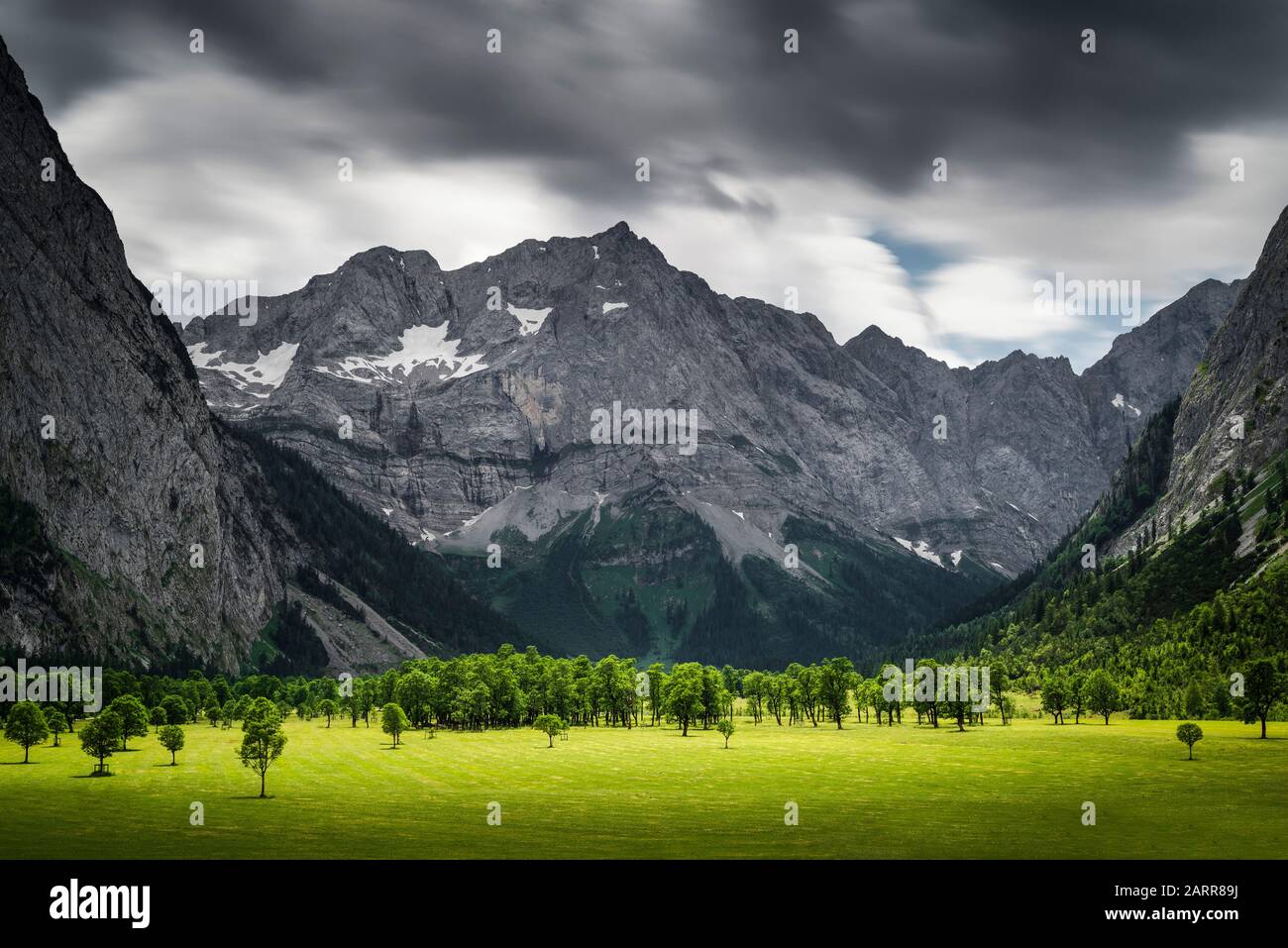 Dunkle Wolken mit Regen und sonnigen Aufhellungen über den felsigen Bergmassiven und Ahornen auf der großen Ahornboden-Weide, in Tyrol, Österreich, Europa Stockfoto
