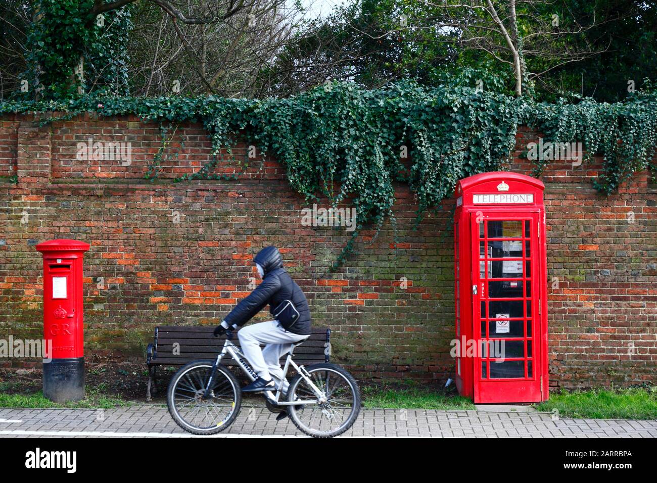 Person, die an der altmodischen Postbox und Telefonbox, Tonbridge, Kent, England, vorbeiradeln kann Stockfoto