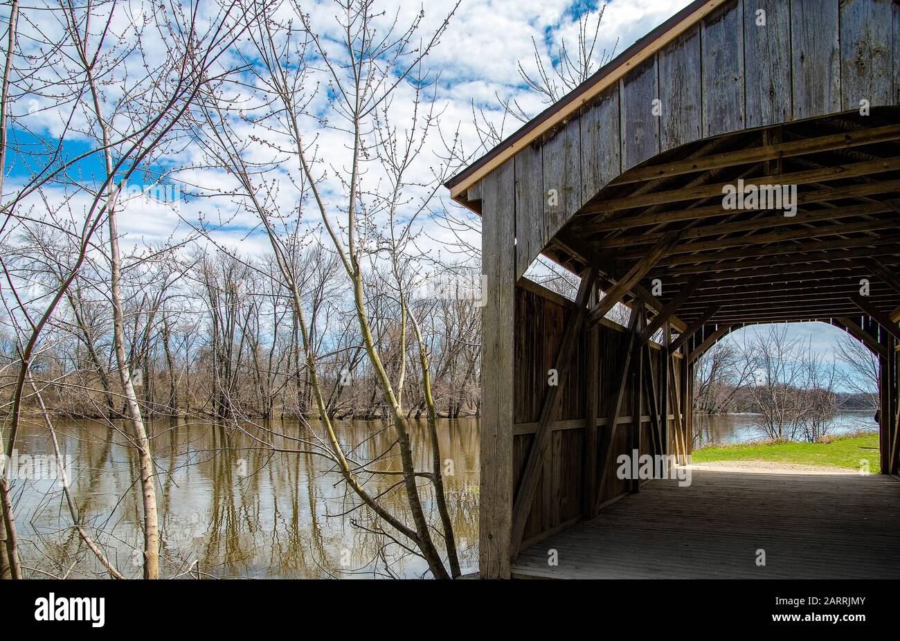 Rustikale Holzbrücke am Fluss im Frühjahr Stockfoto