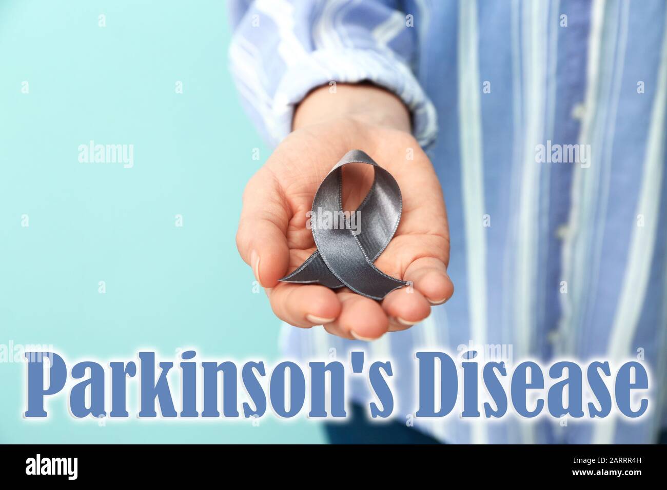 Frau mit silberfarbenem Band auf Farbhintergrund, Nahaufnahme. Konzept der Parkinson-Krankheit Stockfoto