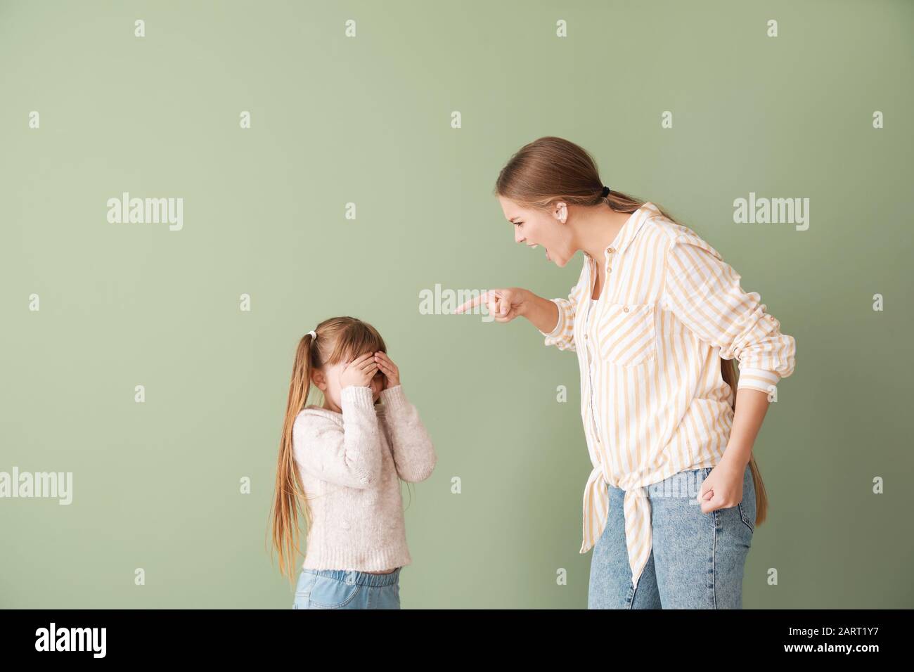 Wütende Mutter schimpft ihre kleine Tochter auf Farbhintergrund Stockfoto