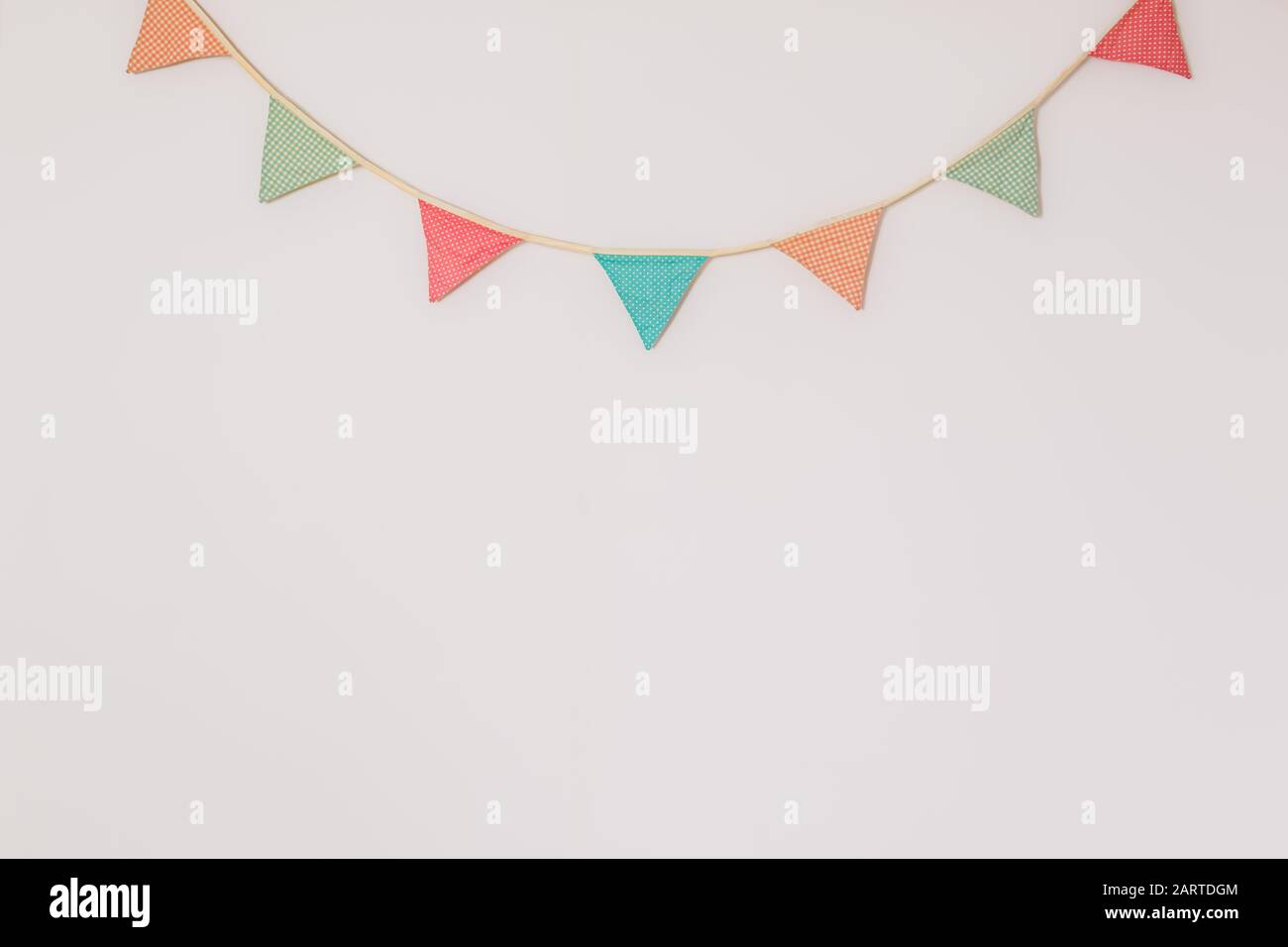 Garland mit niedlichen Partyflaggen, die an der Wand hängen. Hintergrund mit Werbetexten, die die Heimfeier, den Geburtstag oder die festliche Stimmung symbolisieren Stockfoto