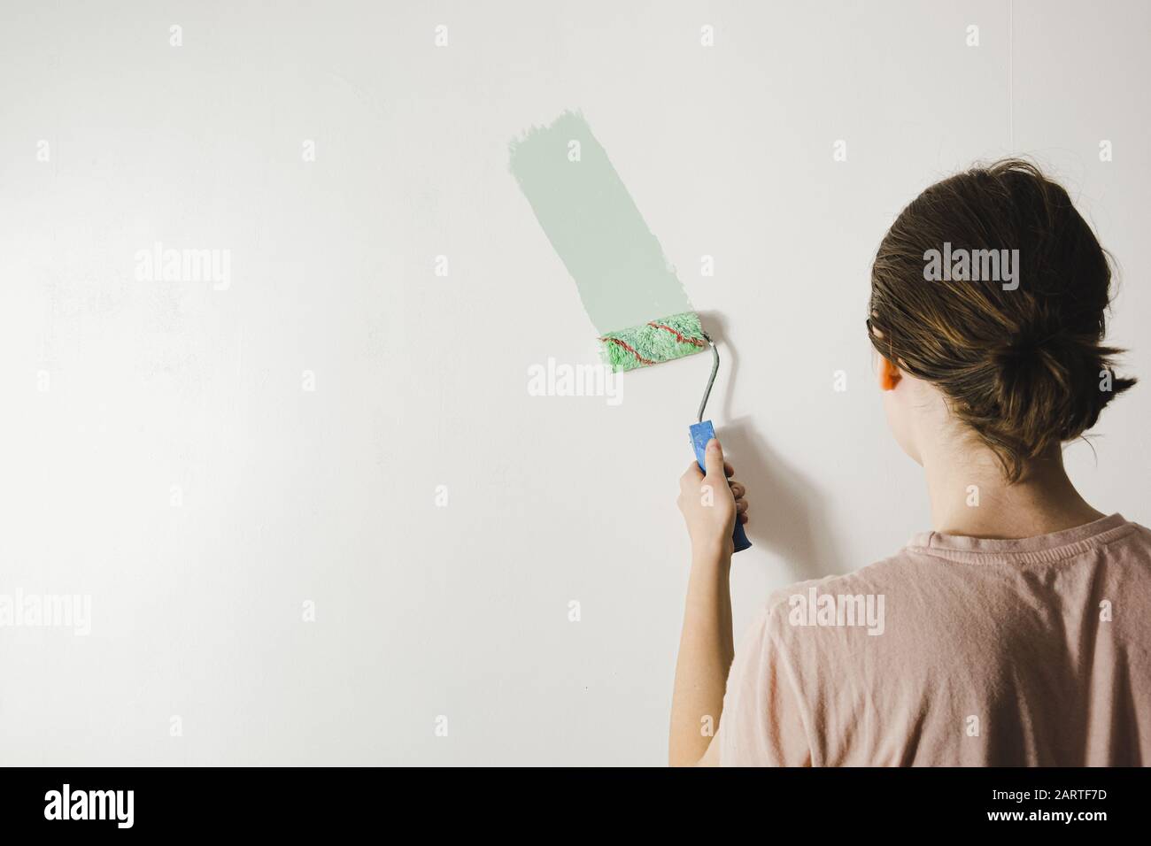 Frau malt eine Hauswand um. Umdekoration, Reparatur, Neubeginn oder Umzug in ein neues Hauskonzept Stockfoto