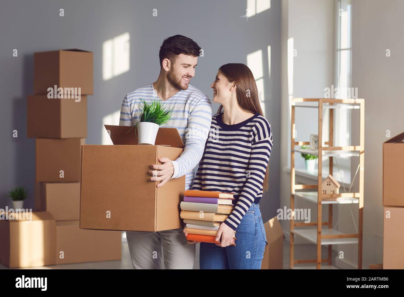 Junge Paar-Familie mit Kisten, die in einem neuen Hausraum umziehen sollen. Stockfoto
