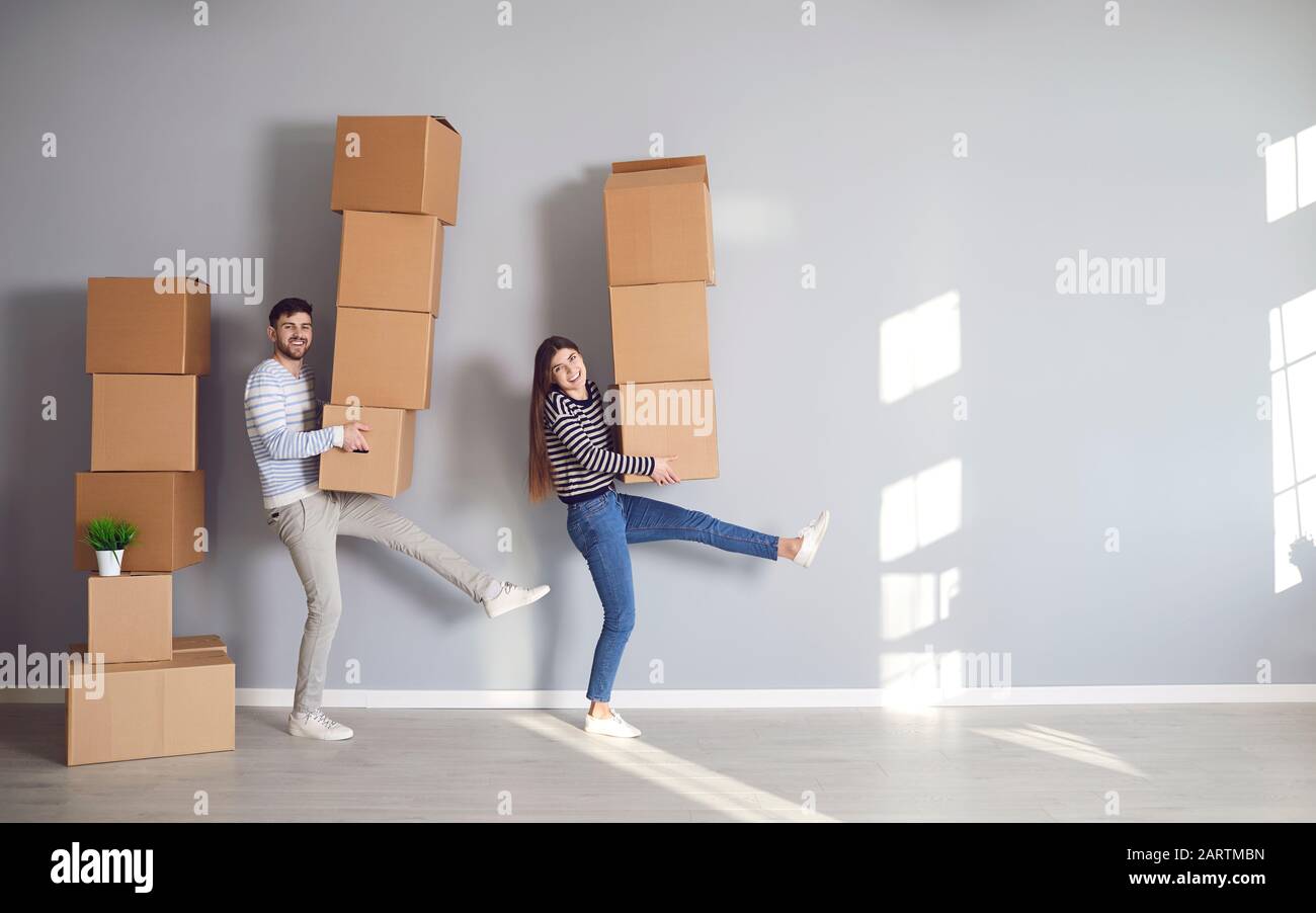 Fröhliches lustiges Paar hält Kartons für den Umzug in ein neues Mehrfamilienhaus Stockfoto