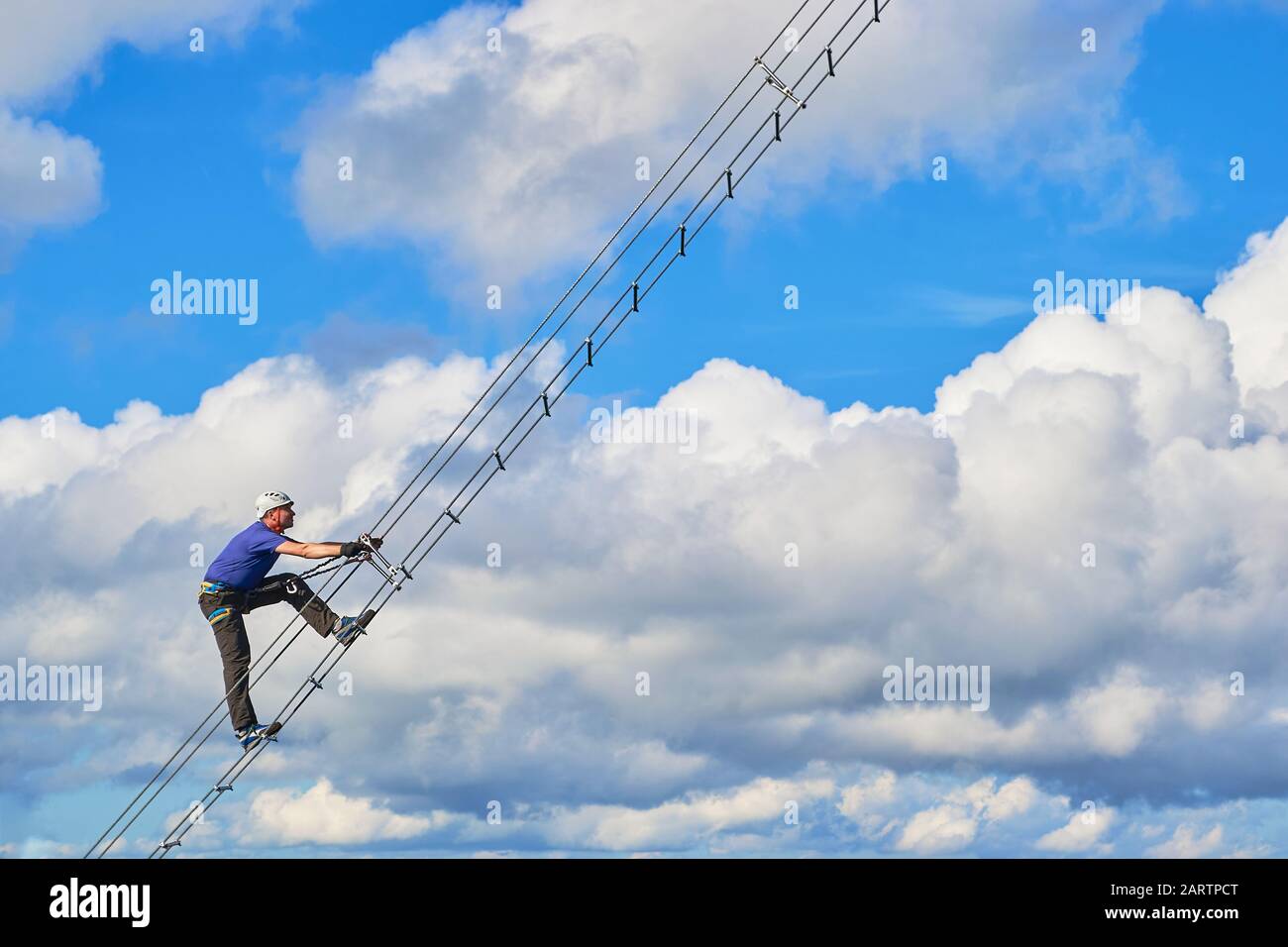 Guy on Via ferrata Intersport, Donnerkogelgebirge, in der Nähe von Gosau, Österreich. Abstrakter Abschnitt einer diagonalen Leiter gegen weiße Wolken und blauen Himmel - s. Stockfoto