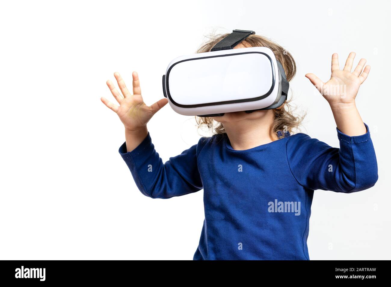 Mädchen trägt blaues Sweatshirt mit Virtual Reality Brille auf weißem Hintergrund Stockfoto