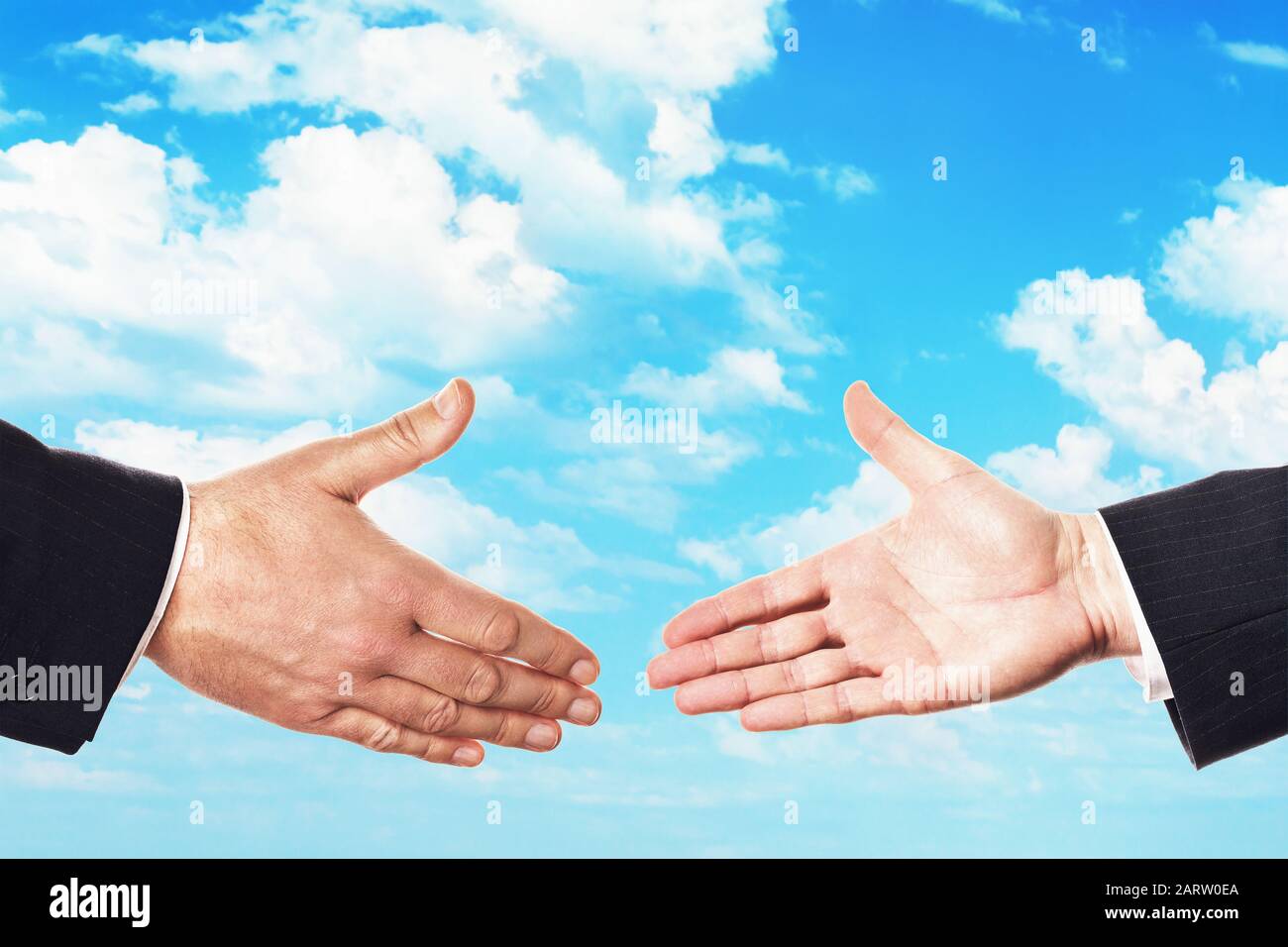 Zwei Menschen halten sich die Hände für einen Handschlag gegen den Himmel. Das Konzept der Transaktion Stockfoto