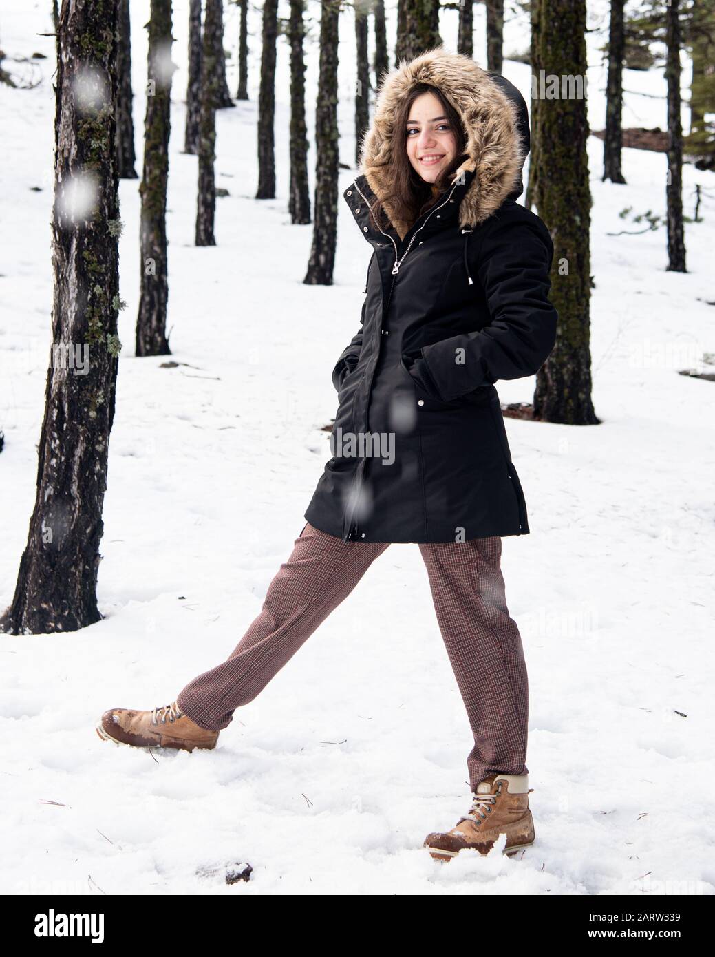 Junges glückliches und wunderschönes Mädchen im Teenager-Alter, das sich in Winterkleidung kleidete und auf Schnee stand und lächelte. Troodos Berge auf Zypern Stockfoto