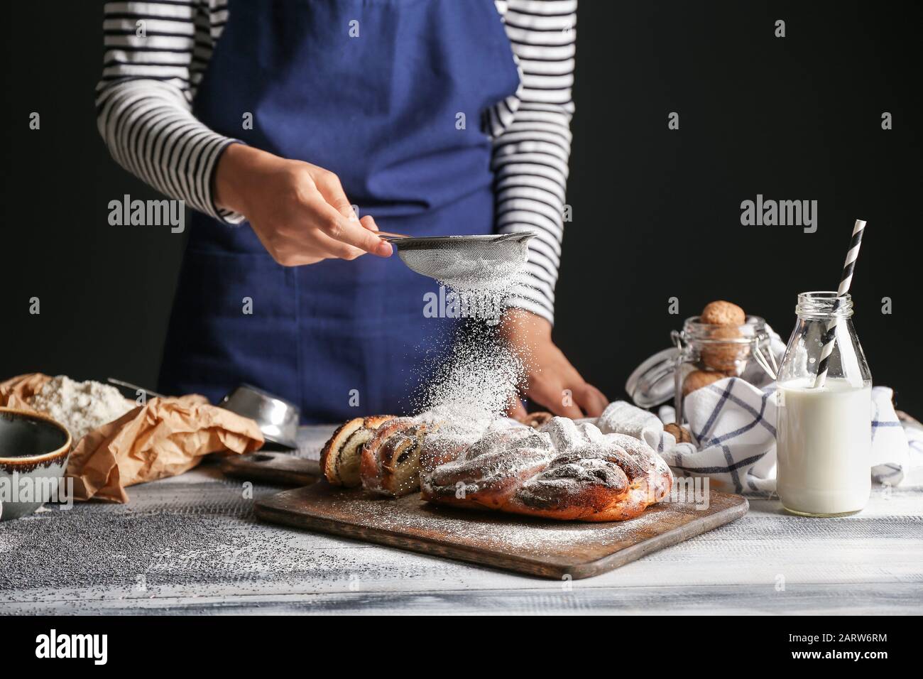 Frau streut Zuckerpulver auf den Tisch Stockfoto