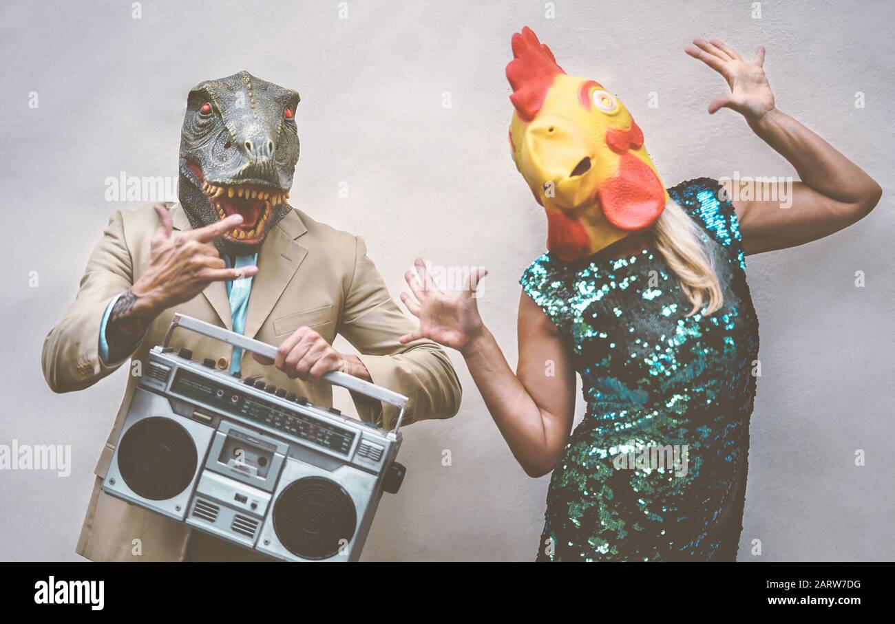 Crazy senior Paar tragen Huhn und T-rex Maske beim Tanzen Outdoor - Reife trendige Leute Spaß haben, Feiern und Musik hören Stockfoto