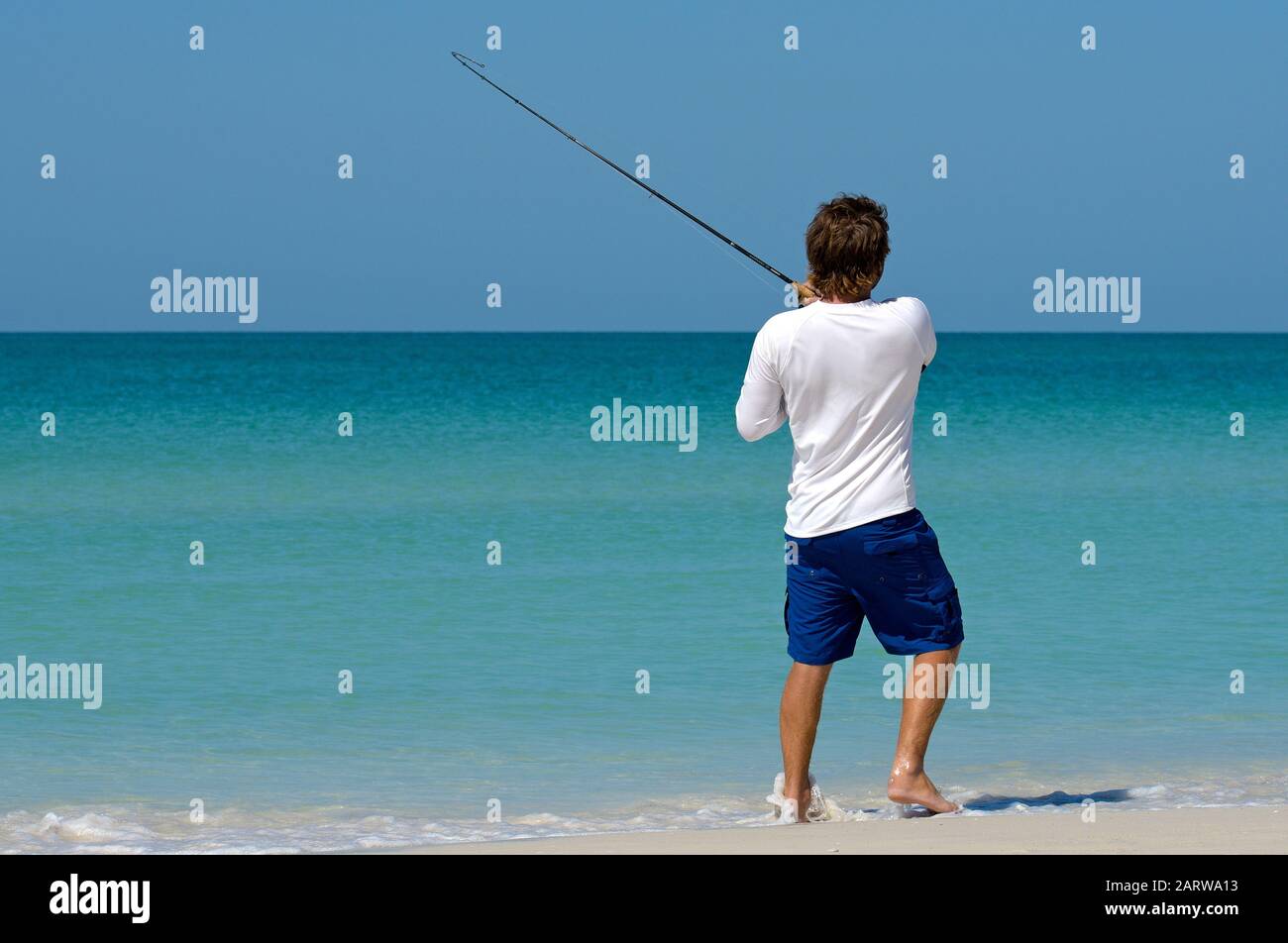 Holmes BEACH, ANNA MARIA ISLAND, FL - 30. April 2018: Ein lokaler junger Mann am Strand, der im Flachwasser des Golfs von Mexiko fischt. Stockfoto