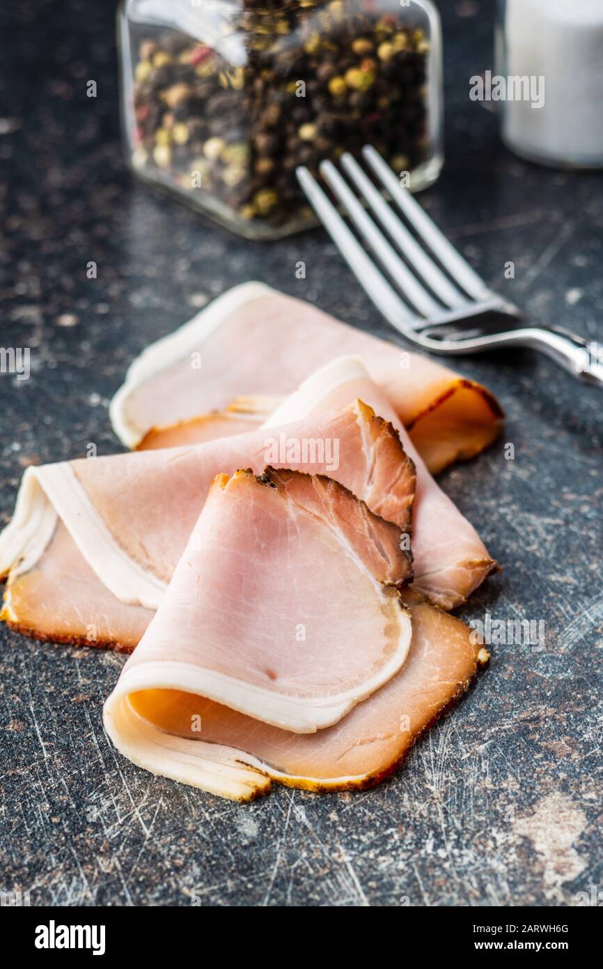 Geräucherter Schinken in Scheiben. Leckeres Schweinefleisch auf dem alten Küchentisch. Stockfoto