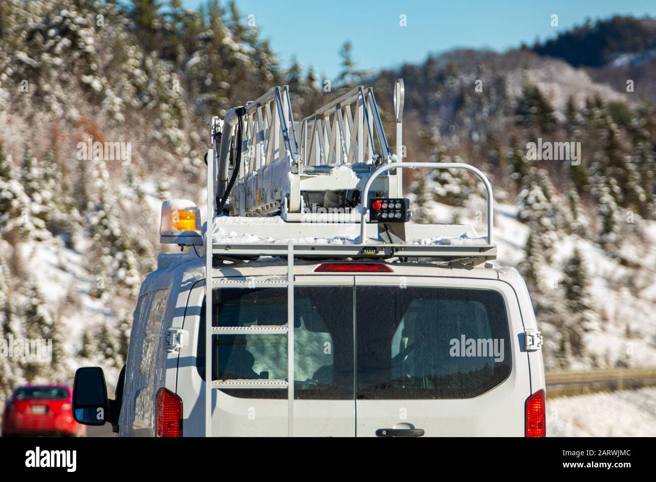 Ein Nutzfahrzeug wird von hinten auf einer Landstraße mit schneebedeckter unscharfer Flucht im Hintergrund mit hydraulischem Auftrieb und Kopierraum gesehen Stockfoto