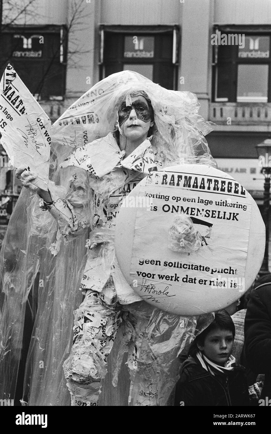Aufführung eines Orchesters der Unemplozenbond auf dem Leidseplein in Amsterdam aus Protest gegen die Ermäßigung auf Leistungen Sympatisant und lebendiges Kunstwerk Fabiola mit einem Strafschild ist der Rabatt auf ein geringes Freigeld unmenschlich und keine Stellenangabepflicht für Arbeiten, die nicht datieren: 26. Februar 1983 Ort: Amsterdam, Noord-Holland Schlüsselwörter: Aktionen, Schnitte, Porträts, soziale Dienste, Straßenkünstler persönlicher Name: Fabiola Stockfoto