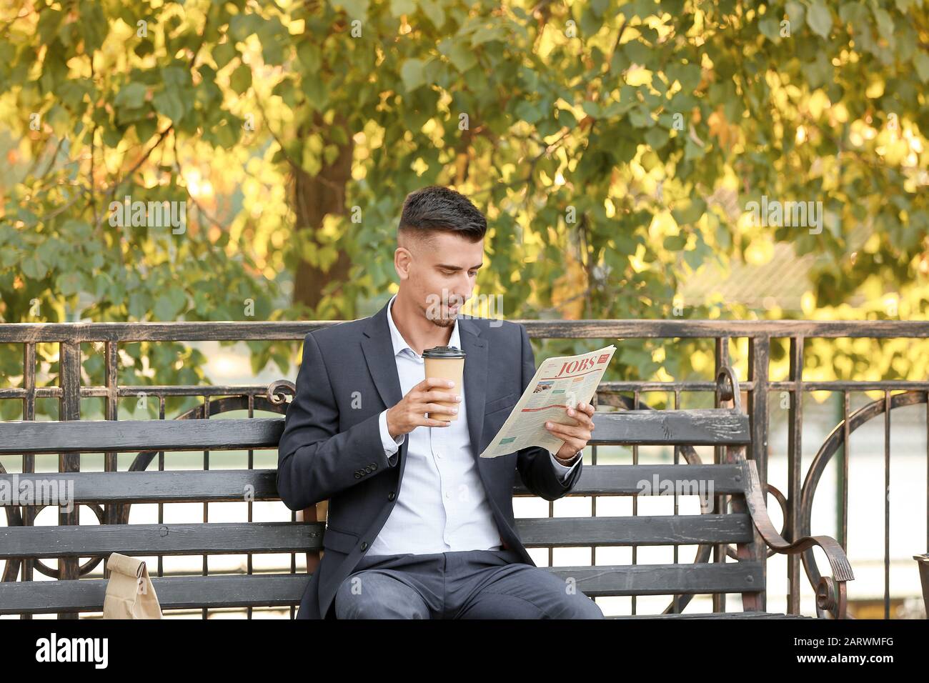 Porträt eines gutaussehenden Geschäftsmannes mit Tasse Kaffee Zeitung im Freien Stockfoto