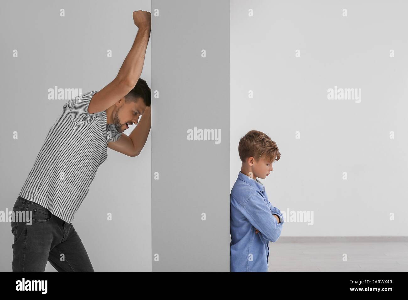 Vater spricht mit seinem kleinen Sohn durch die Mauer. Begriff des Missverständnisses zwischen Eltern und Kindern Stockfoto