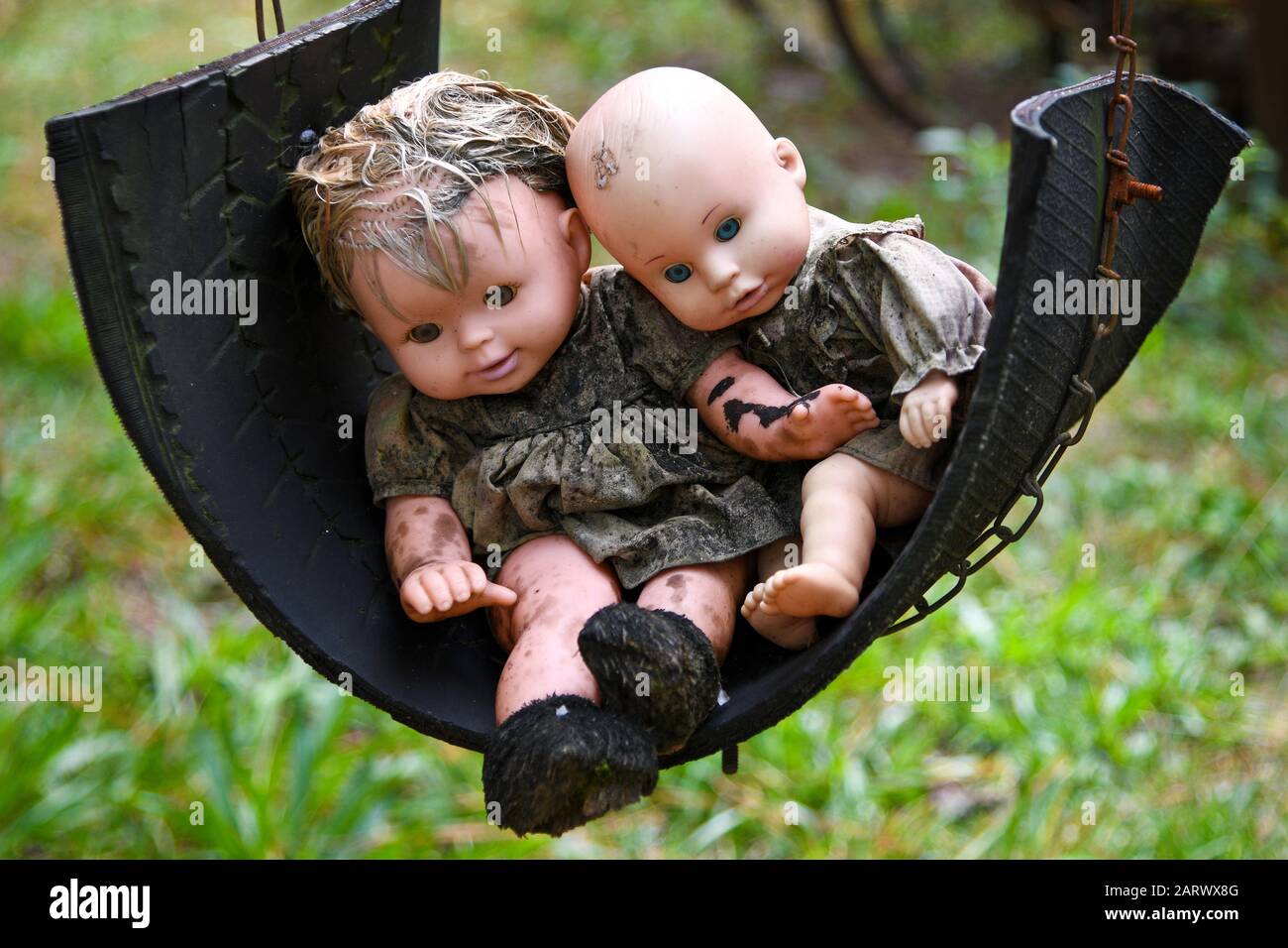 Zwei Gruselige Old Baby Dolls, Die In einem Tire Swing Sitzen Stockfoto