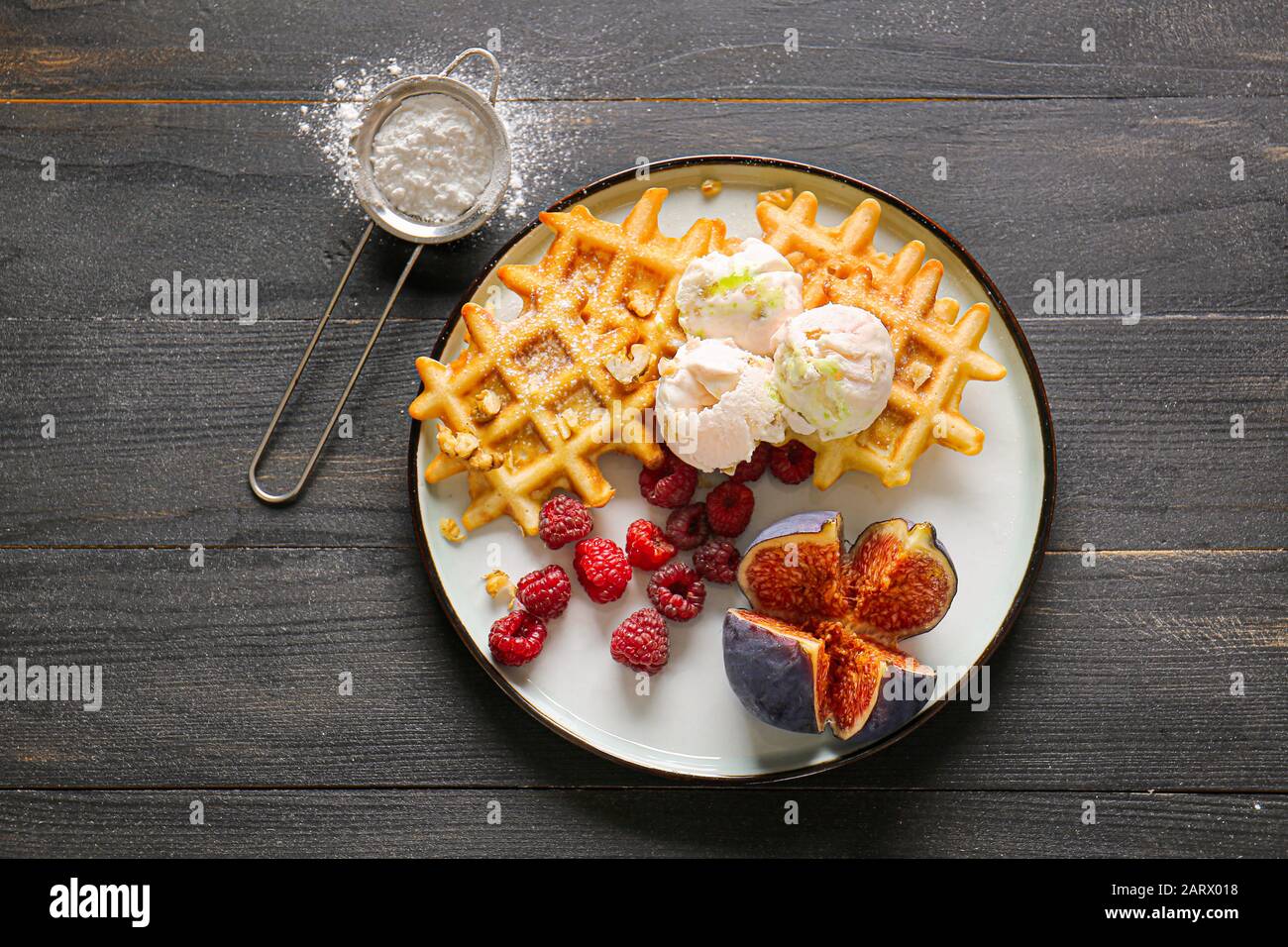 Teller mit leckeren Waffeln, Beeren und Feigen auf dem Tisch Stockfoto