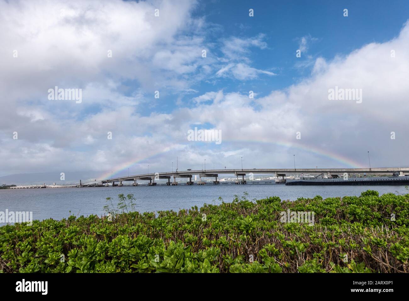 Oahu, Hawaii, USA. - 10. Januar 2020: Pearl Harbor. Rainbow stradelt die Ford Island Brücke unter blauer Coulscape/grünes Laub davor. Stockfoto