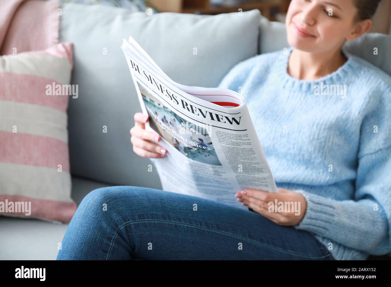 Junge Frau, die Zeitung zu Hause lesen Stockfoto
