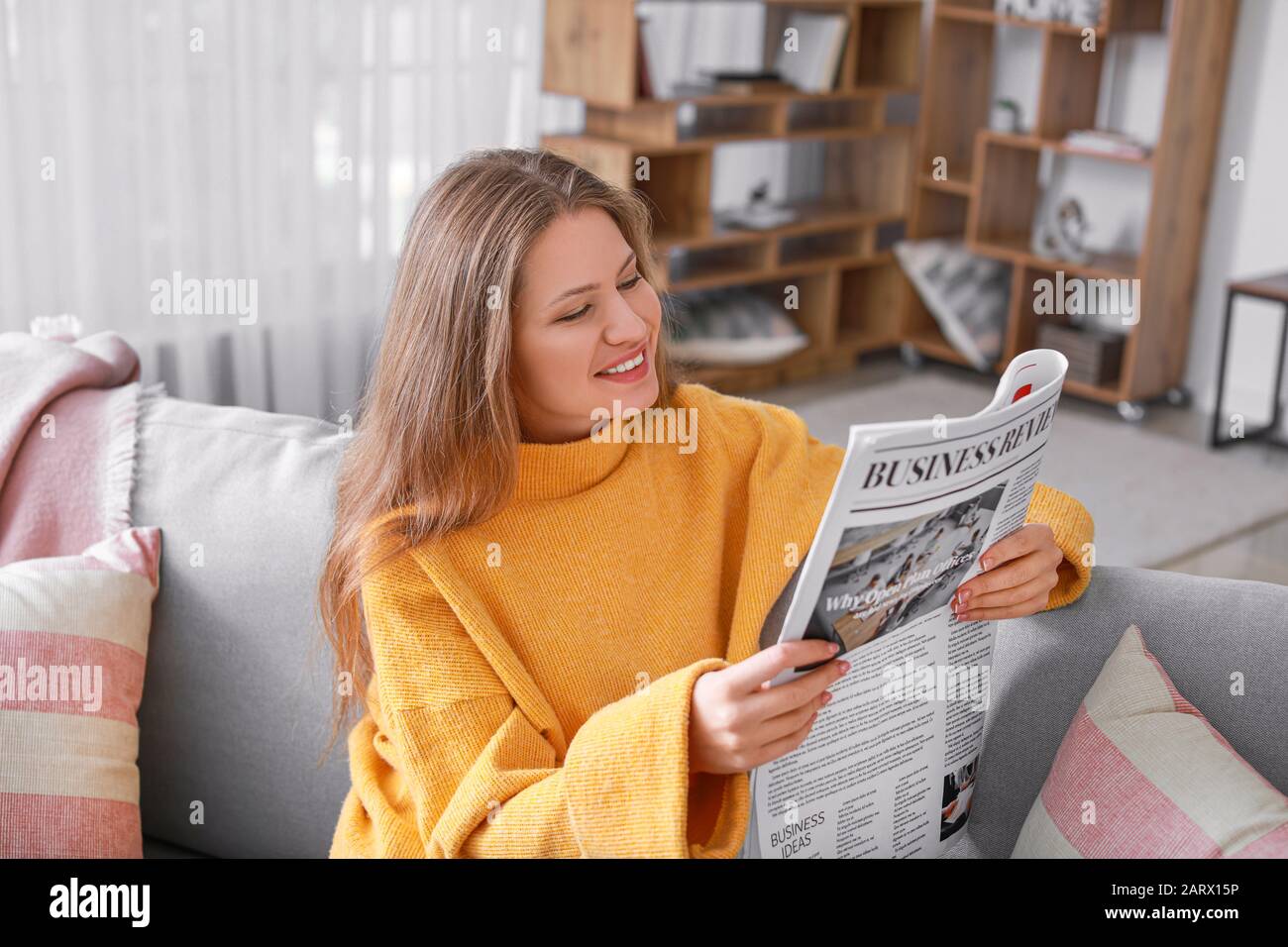 Junge Frau, die Zeitung zu Hause lesen Stockfoto