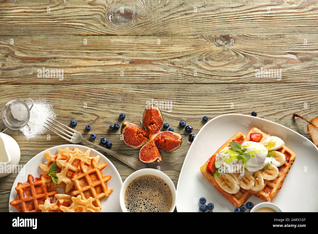Teller mit leckeren Waffeln, Eis und Kaffee auf Holztisch Stockfoto