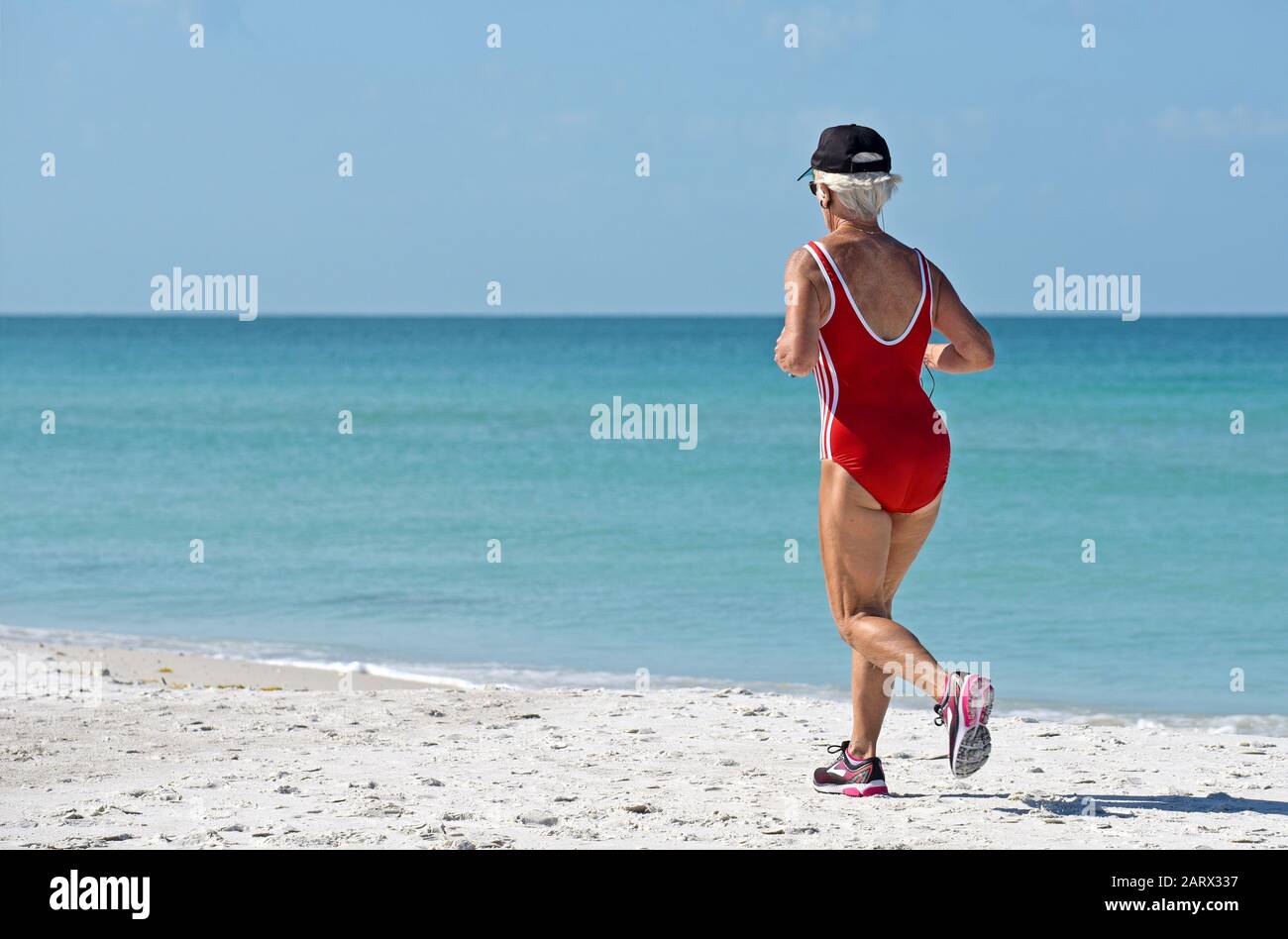 Holmes BEACH, ANNA MARIA ISLAND, FL/USA - 1. Mai 2018: Seniorin Jogging am Strand, die ihre Gesundheit und ihr Wohlbefinden pflegt. Stockfoto