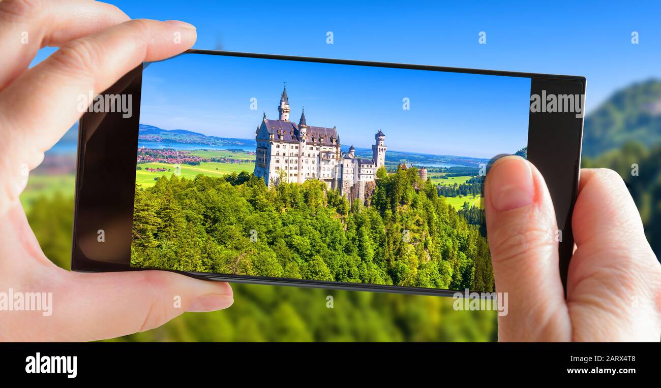 Schloss Neuschwanstein in Bayern. Touristen fotografieren mit dem Handy auf dem berühmten Schloss. Bild der Berglandschaft mit Neuschwanstein auf Stockfoto