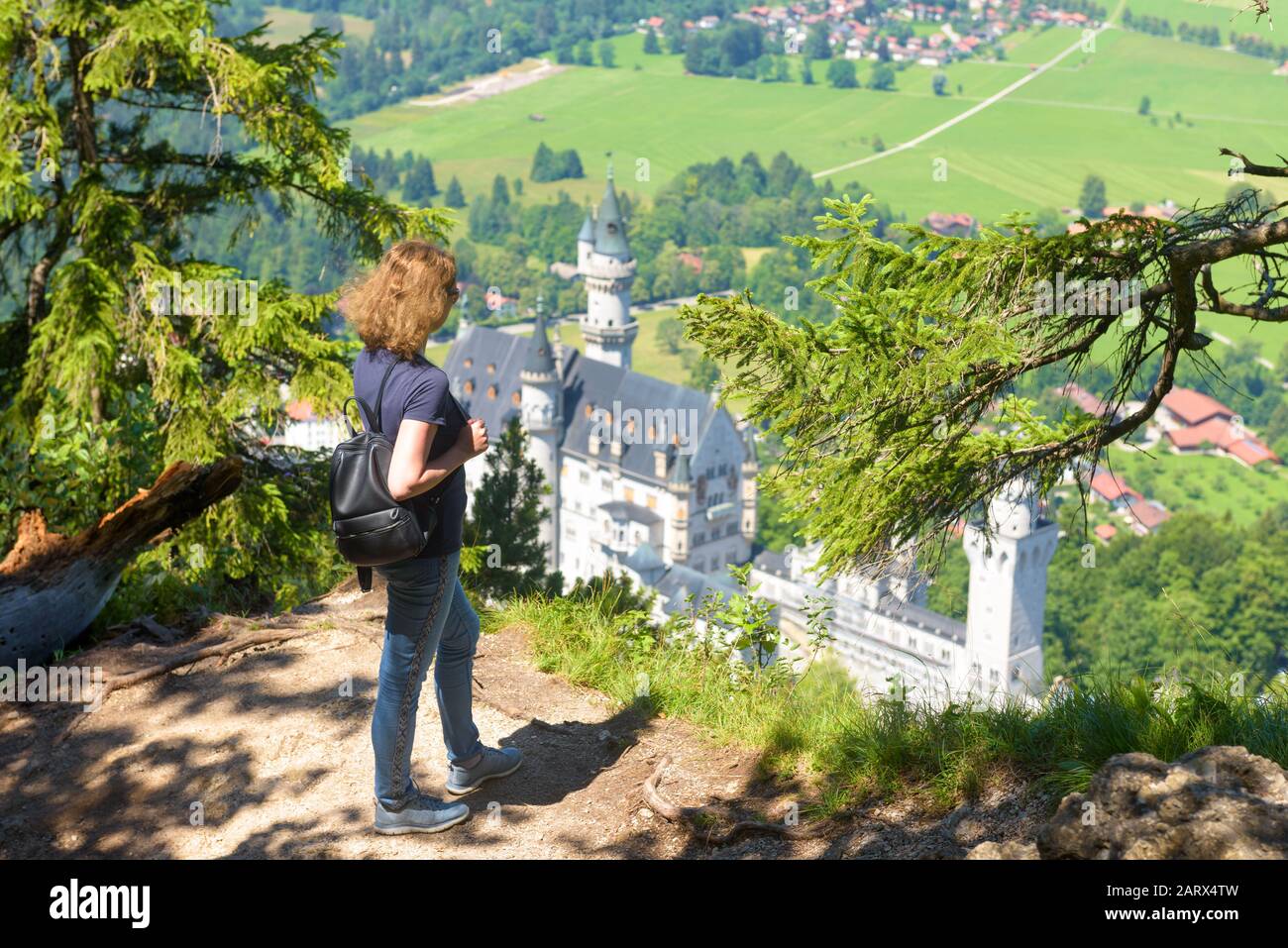 Junge Frau blickt auf Schloss Neuschwanstein, Bayern, Deutschland. Dieses märchenhafte Schloss ist eine Touristenattraktion der deutschen Alpen. Blick auf den berühmten Neuschwanst Stockfoto