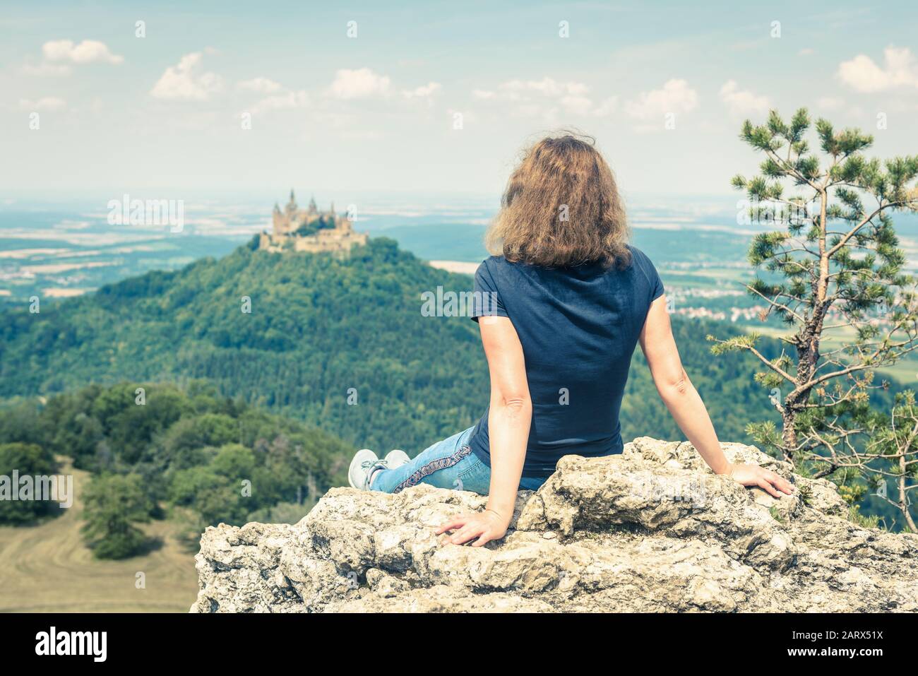 Junge Frau blickt auf die Burg von Hause aus. Es ist eine berühmte Touristenattraktion in der Nähe von Stuttgart. Erwachsenes Mädchen reist in s in den Schwäbischen Alpen Stockfoto