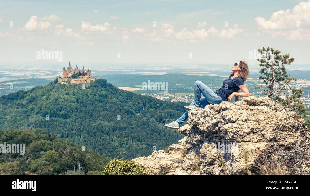 Junge Frau posiert in der Nähe der Burg von Hause aus. Es ist eine berühmte Touristenattraktion in der Nähe von Stuttgart. Erwachsenes Mädchen reist in Schwäbische Alpen ein Stockfoto