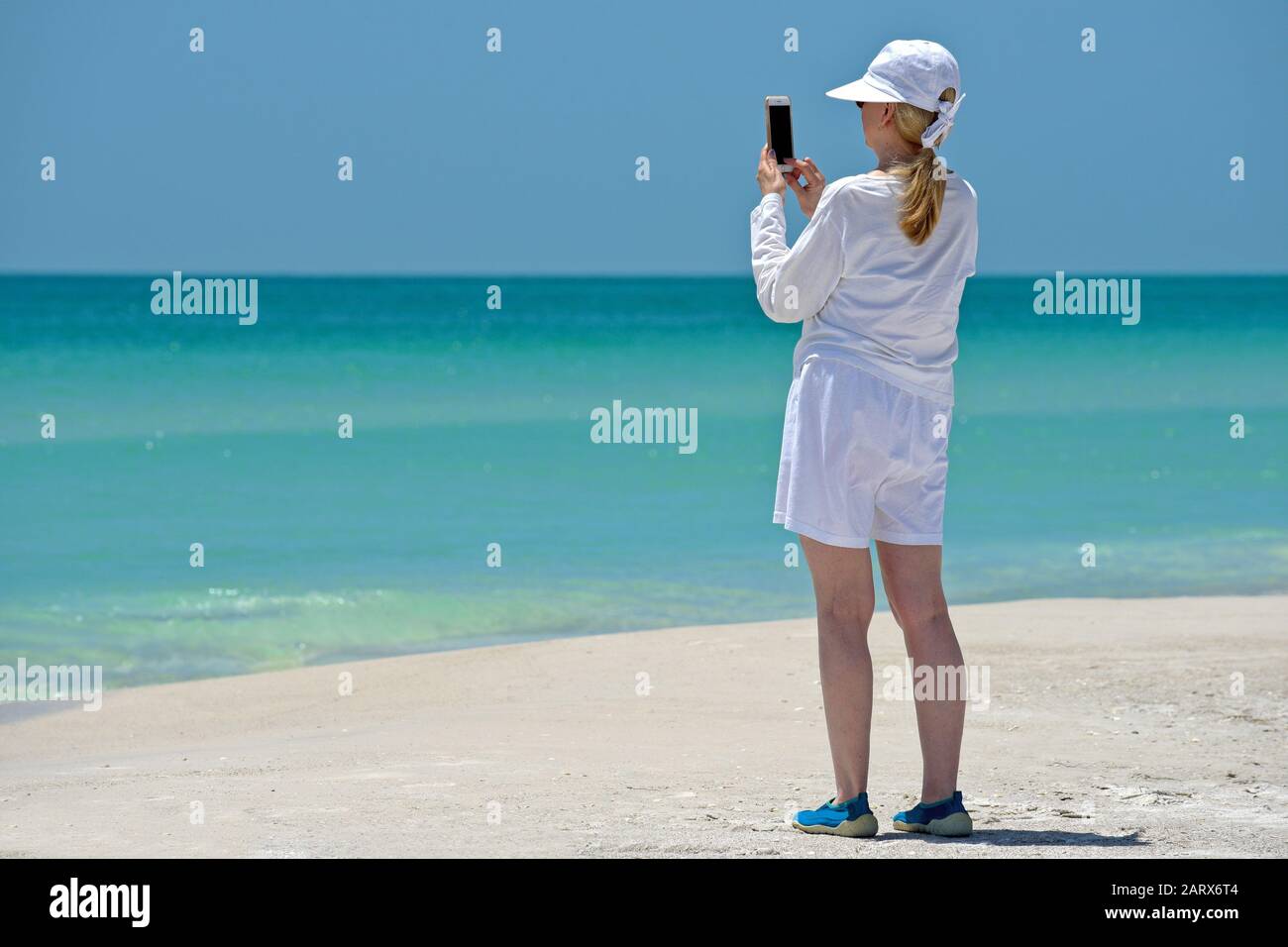 Eine Reife Frau, die mit ihrem Handy am Strand fotografiert Stockfoto