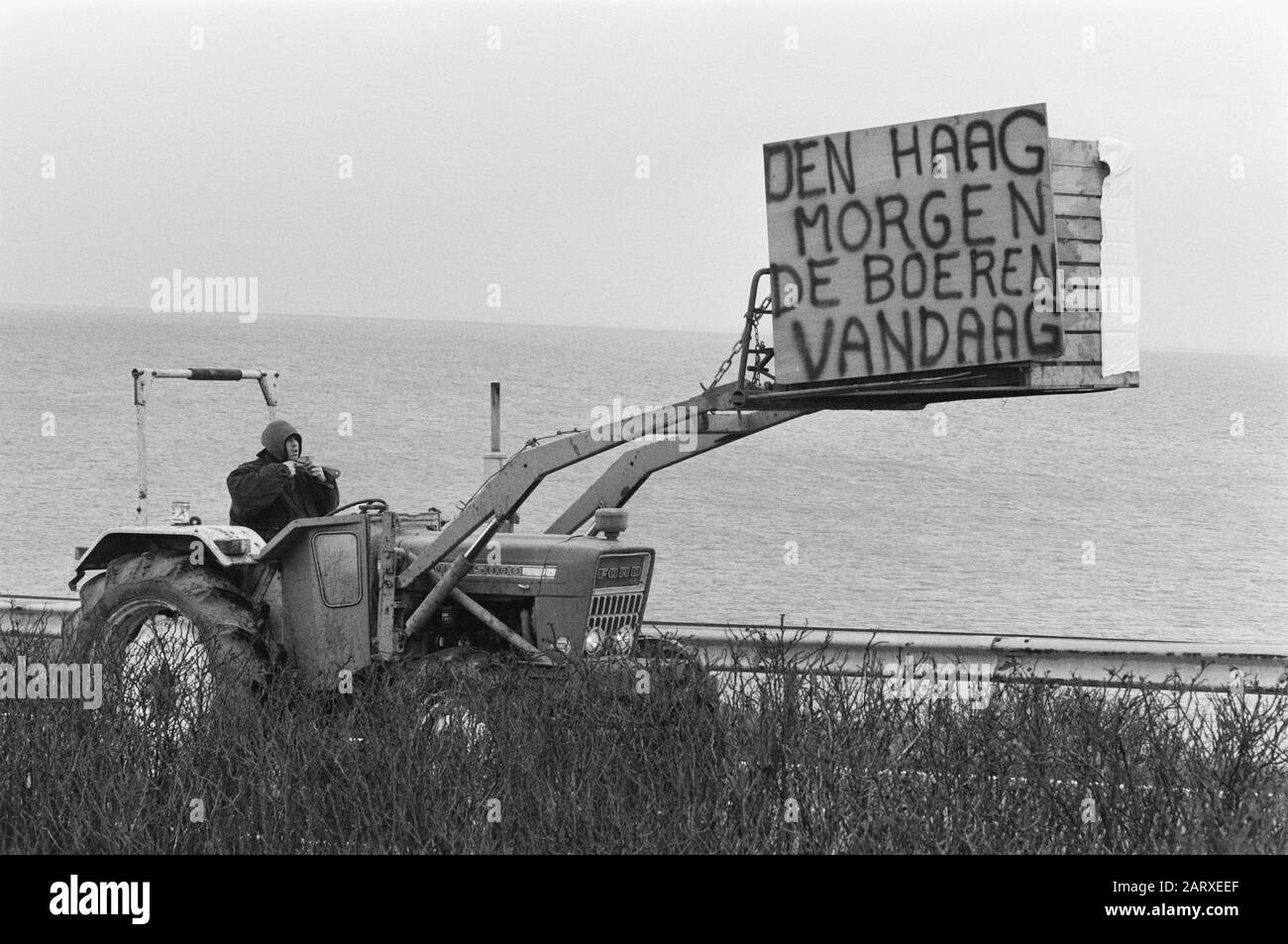 Die Landwirte führen aus Protest gegen die Traktoren der Landwirtschaftspolitik eine Staffelleise mit einer Protesttafel an ihrem Gabeldatum: 27. Februar 1989 Standort: Afsluitdijk Schlüsselwörter: Slogs, Protestschilder, Proteste, Traktoren Stockfoto
