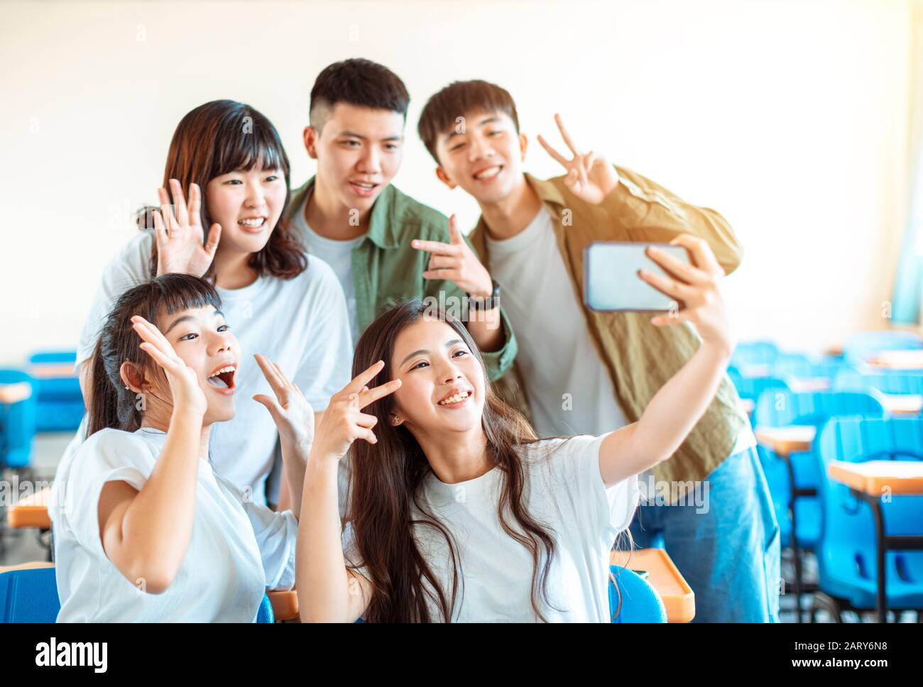 Fröhliche junge Gruppe von Teenagern, die Spaß an selfie im Klassenzimmer machen Stockfoto