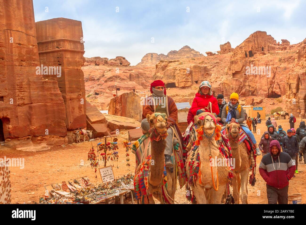 Petra, Jordanien - 4. Januar 2020: Beduinen und Touristen fahren in den monumentalen Petra, UNESCO-Weltkulturerbe, einer historischen und archäologischen Stätte, mit verdrossener Kamele Stockfoto