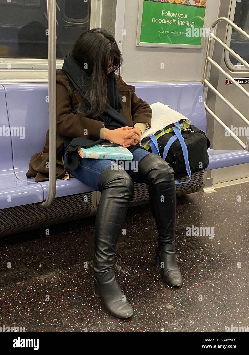 Frau ruht während der Fahrt mit einem U-Bahn-Zug in Brooklyn, New York. Stockfoto