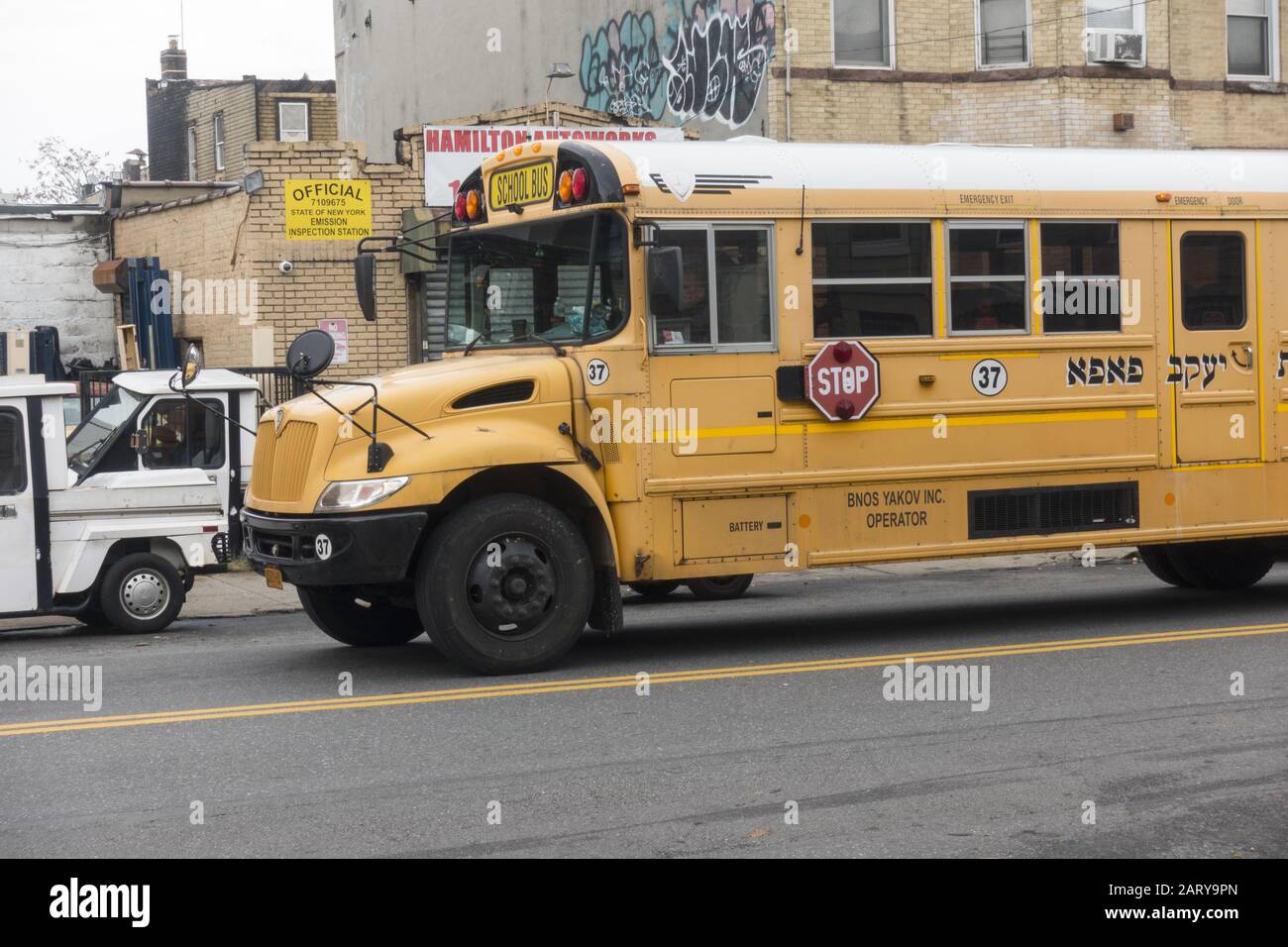 Schulbus einer orthodoxen jüdischen Grundschule mit hebräischer Schrift im Stadtviertel Borough Park in Brooklyn, New York. Stockfoto
