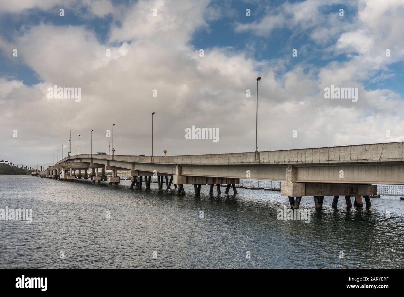 Oahu, Hawaii, USA. - 10. Januar 2020: Pearl Harbor. Ford Island Pontonbrücke schäumt beige Betonlinie zwischen grauem Wasser und blauer Wolkenlandschaft. Stockfoto