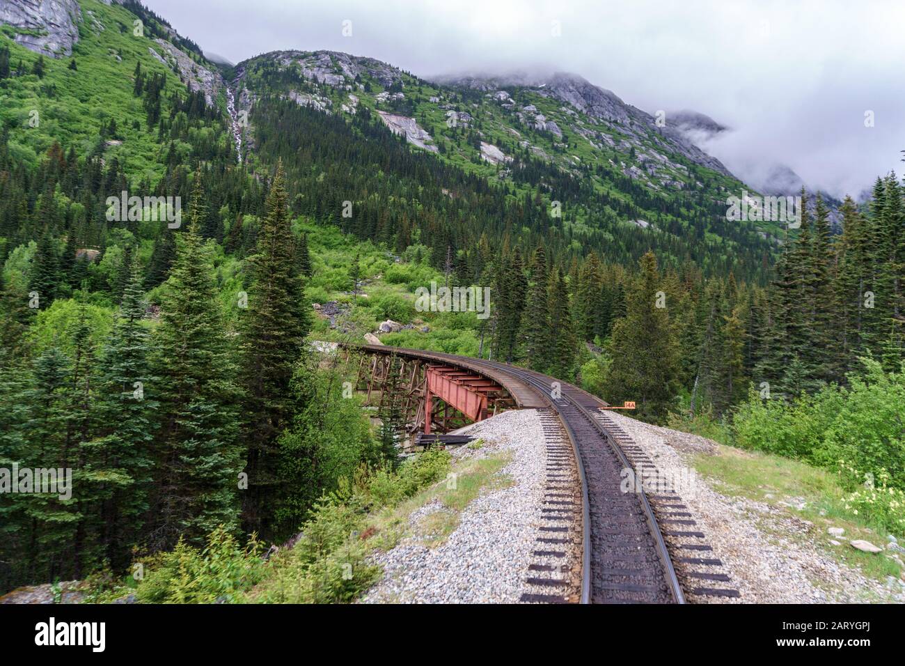 Eisenbahn im Regenwald. Die Brücke aus rotem Metall ist sehr alt und schön. Foto aus dem Zug. Erstaunliche Natur, Wasserfall und Tierwelt sind hier sehr verbreitet. Stockfoto