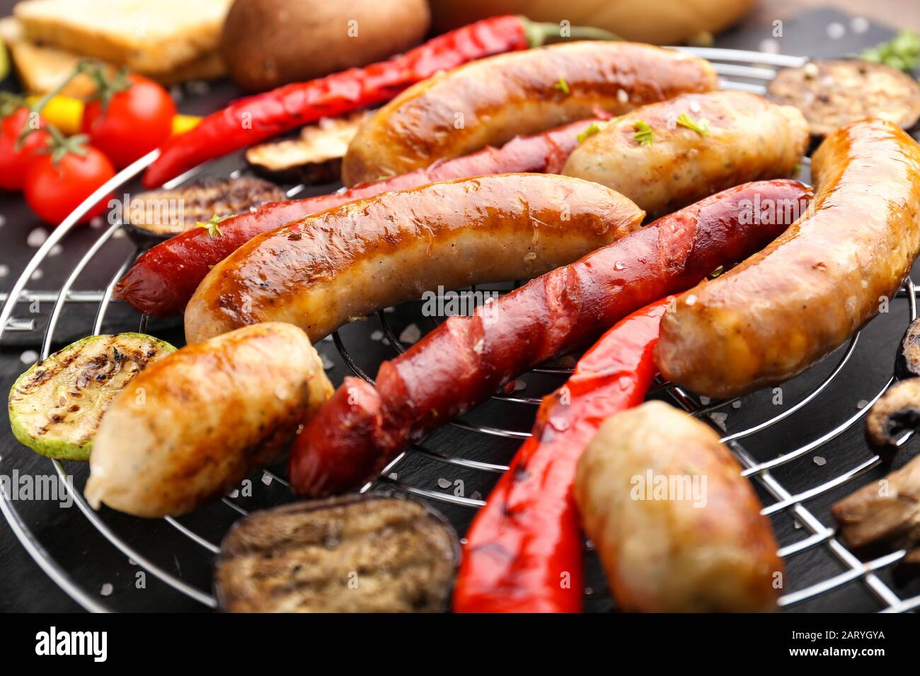 Leckere gegrillte Würstchen mit Gemüse am Gitter, in der Nähe Stockfoto